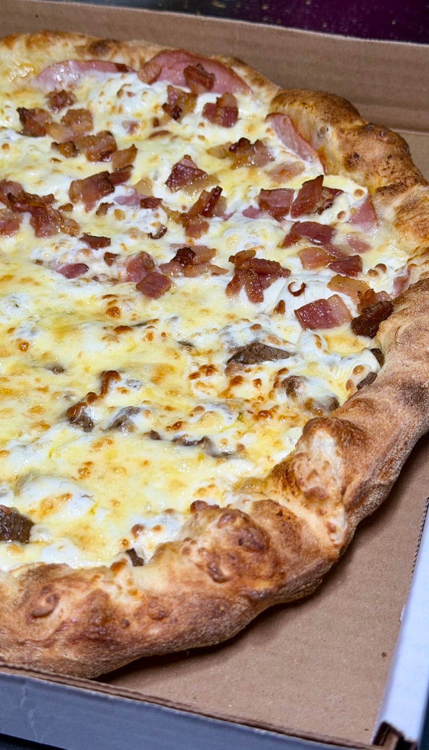 Pizza da Luigi’s com massa dourada, queijo e bacon